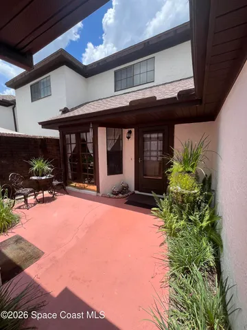 a view of a house with potted plants and a table and chairs