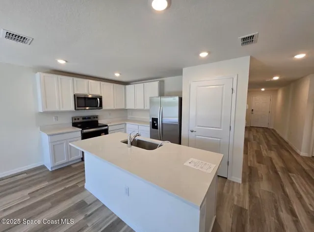 a kitchen with sink a refrigerator and white cabinets