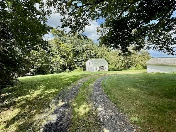 a view of a big house with a big yard and large trees