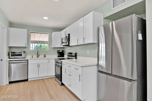 a kitchen with white cabinets stainless steel appliances and a window