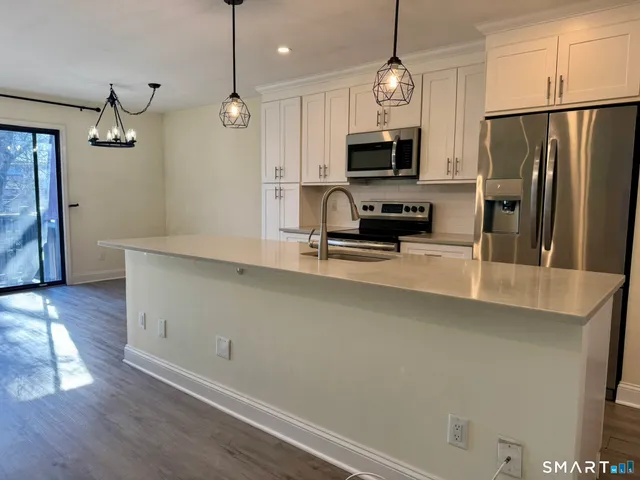 a kitchen with kitchen island white cabinets and stainless steel appliances