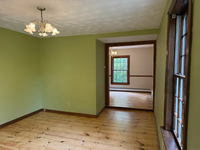 a view of empty room with wooden floor and kitchen