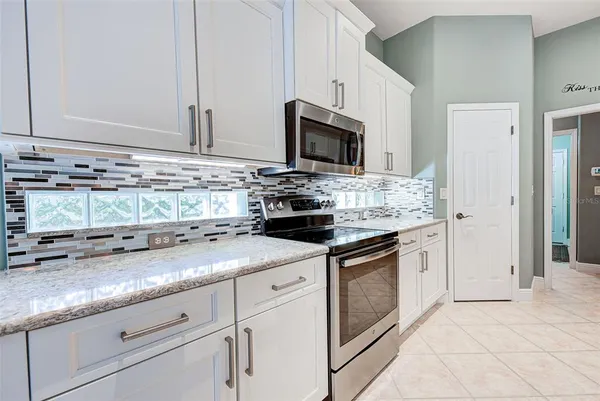 a kitchen with granite countertop white cabinets and white appliances