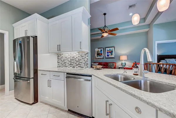 a kitchen with stainless steel appliances granite countertop a sink a refrigerator and a refrigerator