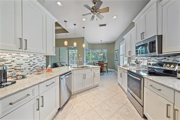 a kitchen with kitchen island granite countertop a sink stainless steel appliances and white cabinets