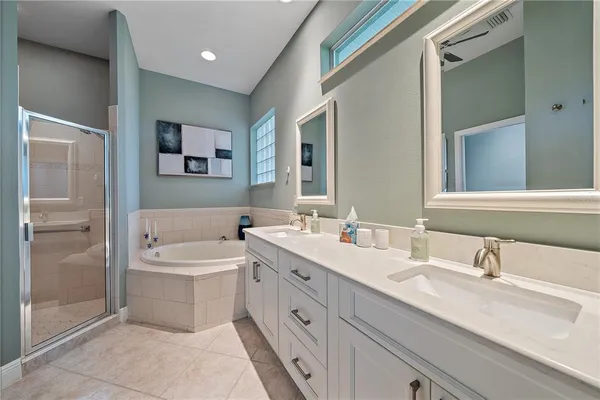 a spacious bathroom with a double vanity sink mirror and bathtub
