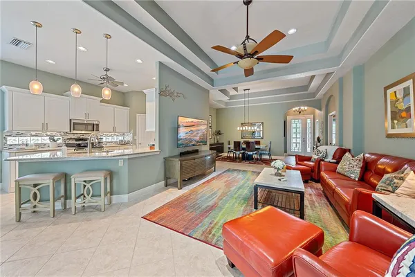 a living room with lots of furniture kitchen view and a chandelier