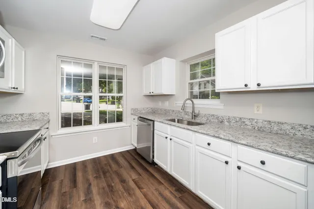 a kitchen with granite countertop white cabinets and a sink