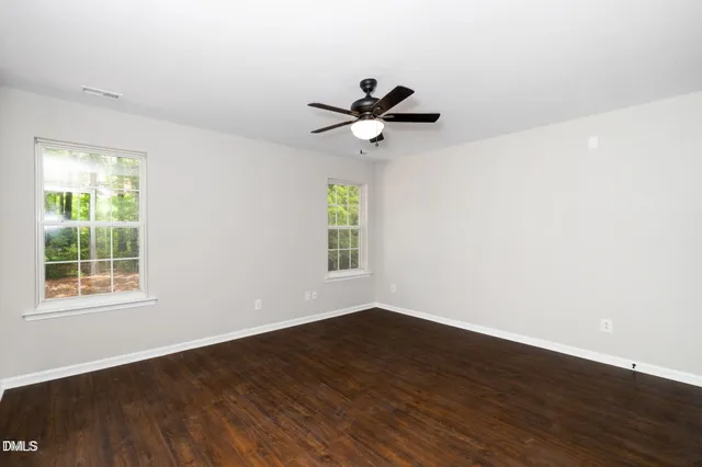 a view of a big room with wooden floor and windows