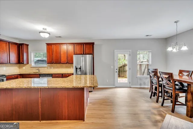 a kitchen with stainless steel appliances granite countertop wooden floors and wooden cabinets