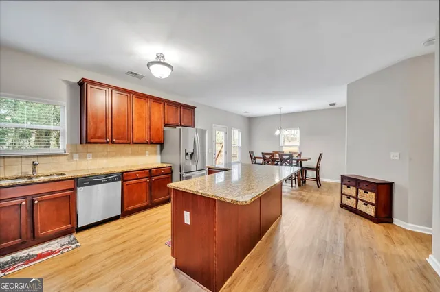 a large kitchen with stainless steel appliances granite countertop a sink dishwasher a stove and a refrigerator