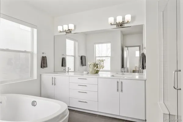 a bathroom with a double vanity sink a mirror and a bathtub