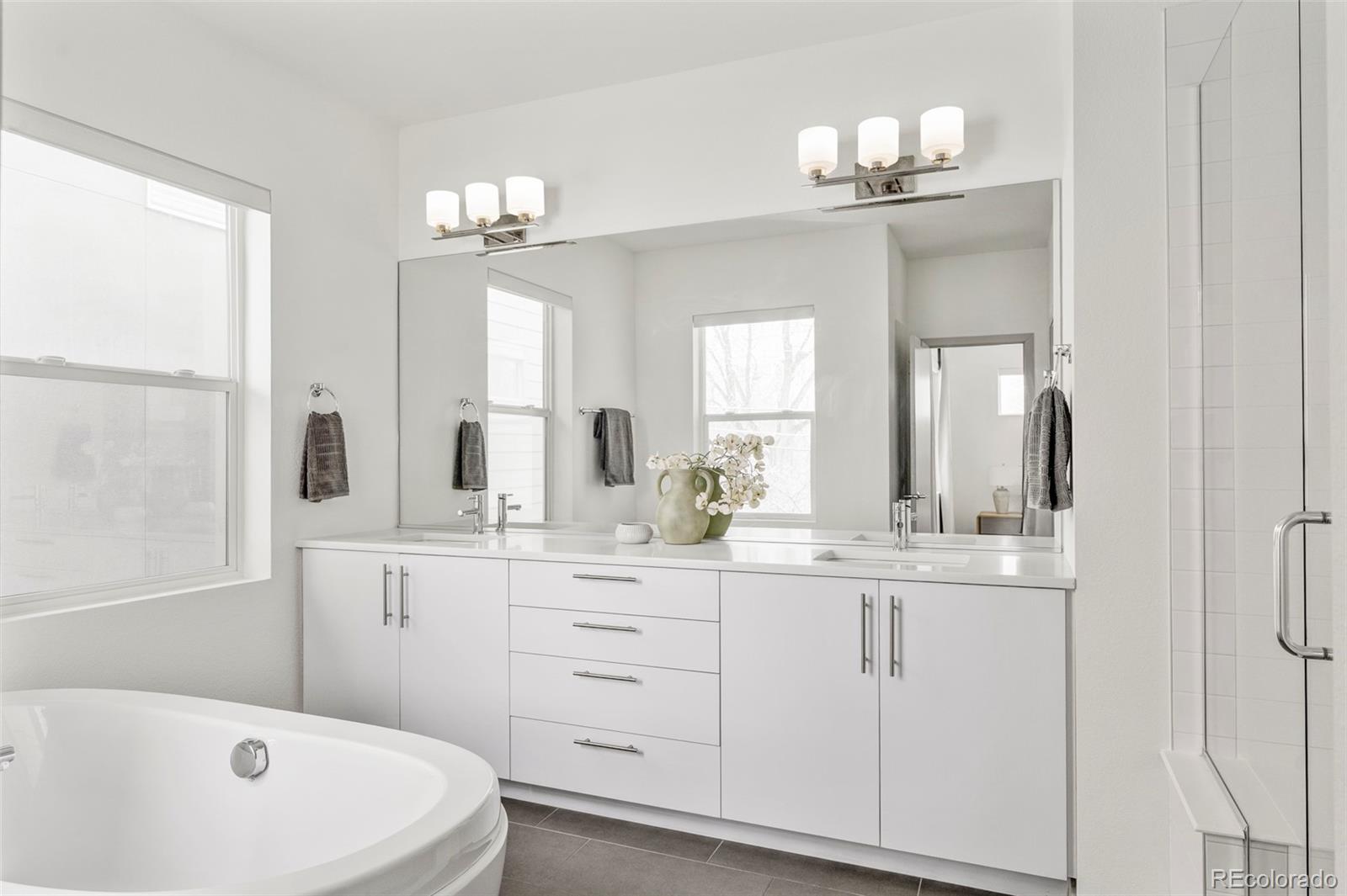 4015 Fenton Court Wheat Ridge, CO 80212 - Photo 12 of 31 a bathroom with a double vanity sink a mirror and a bathtub
