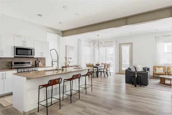 a kitchen with stainless steel appliances granite countertop a stove top oven a sink a dining table and chairs with wooden floor