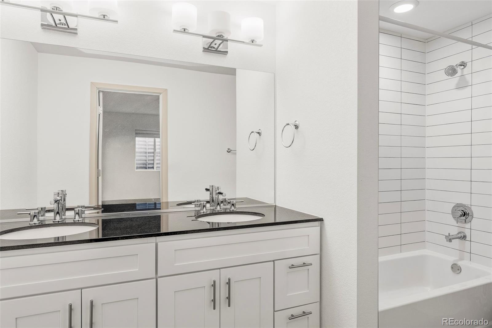 4015 Fenton Court Wheat Ridge, CO 80212 - Photo 21 of 31 a bathroom with a granite countertop sink a mirror a shower and a bathtub