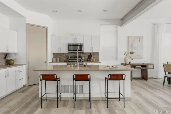 a kitchen with white cabinets and chairs