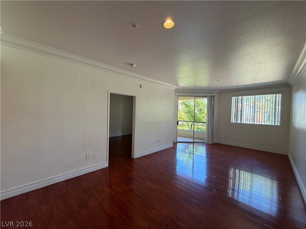 210 East Flamingo Road, Unit 126 Las Vegas, NV 89169 - Photo 5 of 16 Rich hardwood floors reflect light from the sliding glass door leading to a private balcony.