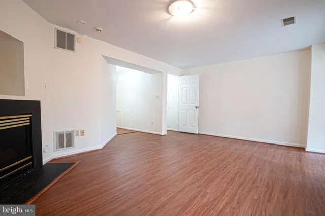 a view of empty room with wooden floor and fireplace