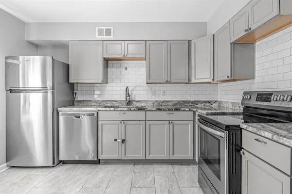 a kitchen with stainless steel appliances granite countertop a refrigerator sink and stove