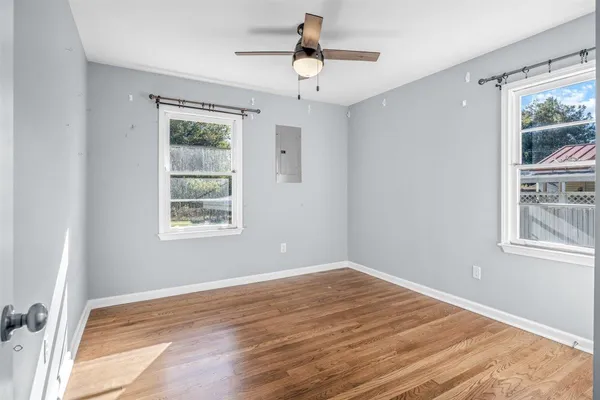 a view of an empty room with window and wooden floor