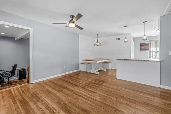 a view of an empty room with wooden floor and a window