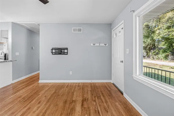 a view of an empty room with window and wooden floor