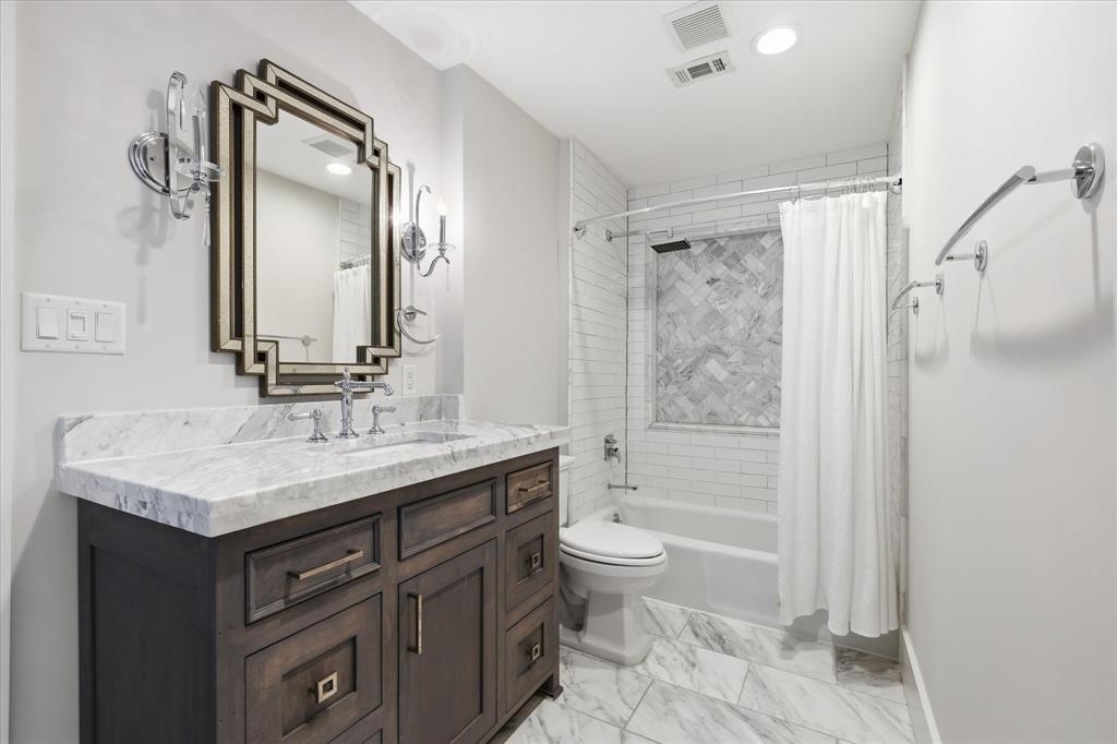 4310 Forest Bend Road Dallas, TX 75244 - Photo 29 of 40 Bathroom featuring a wood vanity with a white countertop and undermount sink, geometric mirror, and sconce lighting