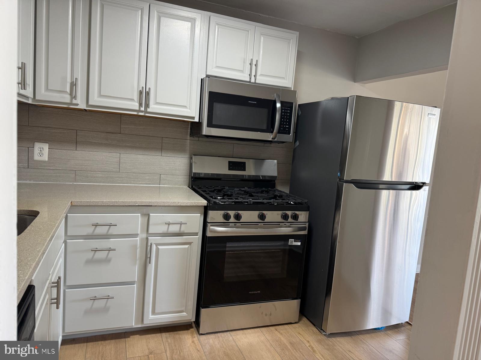 a kitchen with white cabinets and stainless steel appliances