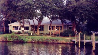 a front view of a house with a yard and large trees