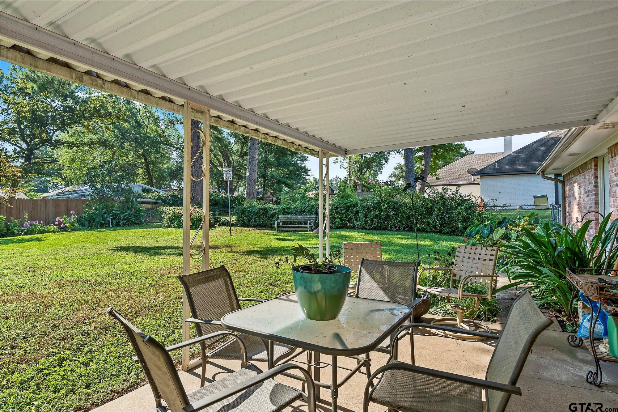 3724 Pollard Drive Tyler, TX 75701 - Photo 26 of 28 a view of a patio with table and chairs potted plants and palm trees