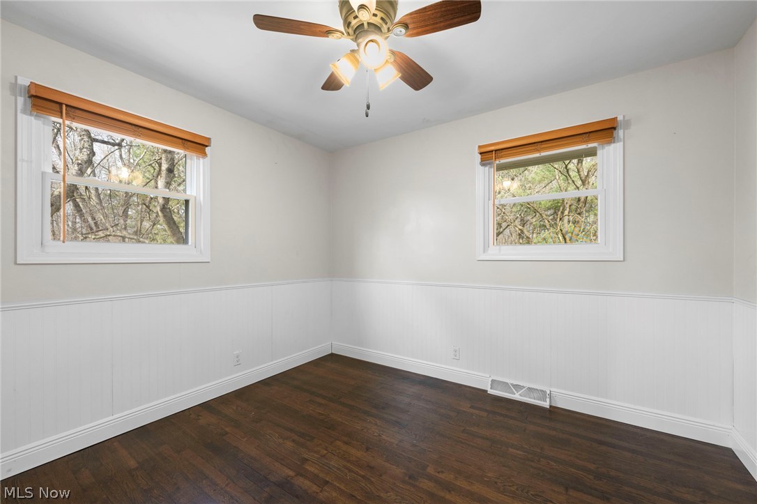 1835 Windham Road Newton Falls, OH 44444 - Photo 17 of 40 Empty room featuring dark wood-style floors, ceiling fan, plenty of natural light, and wainscoting