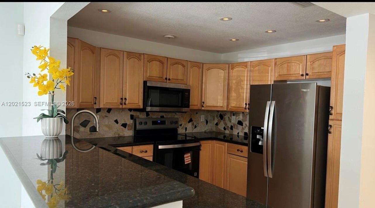a kitchen with stainless steel appliances granite countertop a refrigerator sink and stove