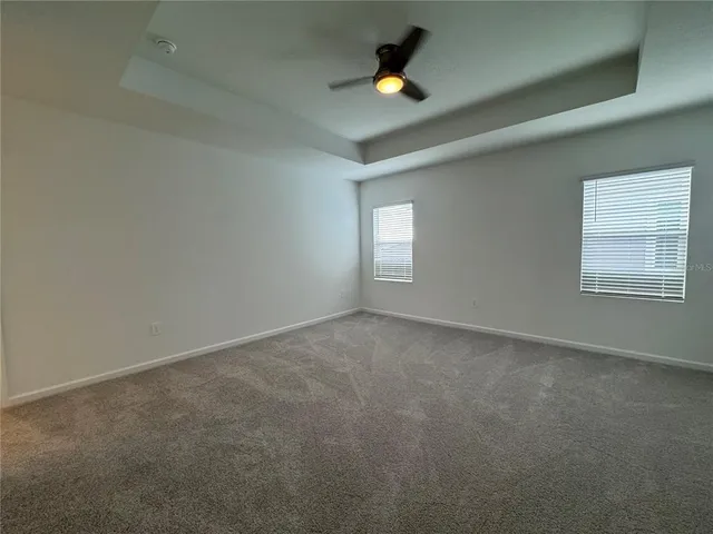 an empty room with window and fan in ceiling room