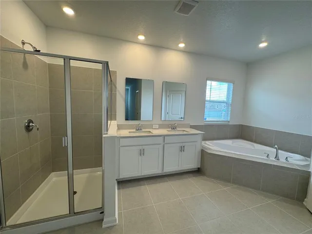 a bathroom with a bathtub a double vanity sink and mirror
