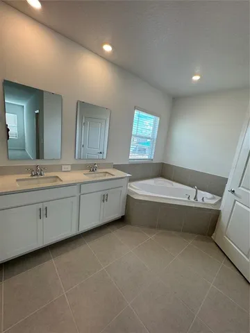 a spacious bathroom with a double vanity sink a mirror and a bathtub