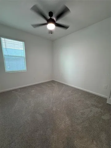 an empty room with a chandelier fan and windows