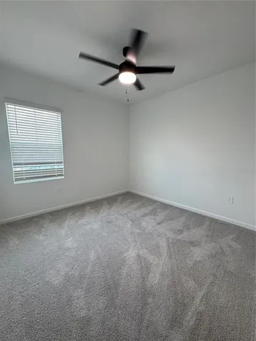 an empty room with a ceiling fan and window
