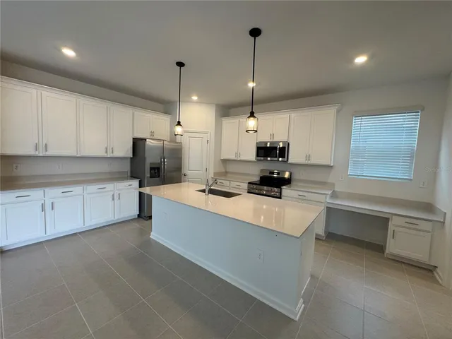 a large kitchen with stainless steel appliances a stove sink and cabinets