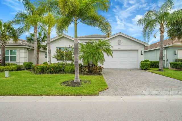 a front view of a house with a garden and palm trees