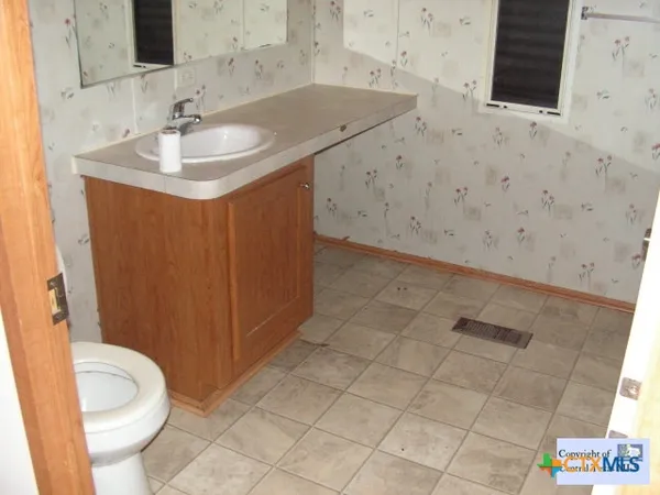 a bathroom with a granite countertop sink a toilet and a mirror