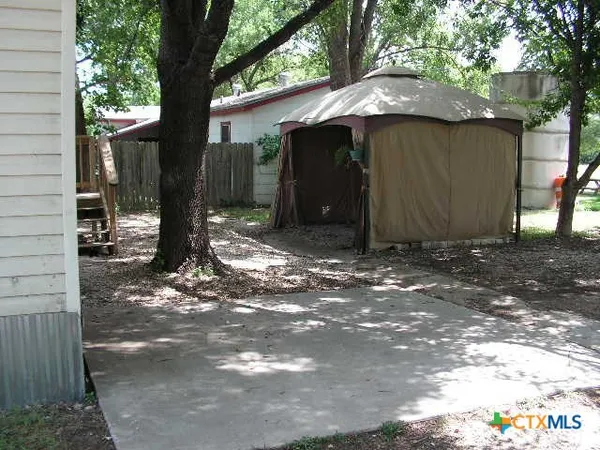 a view of a barn with a small yard and a large tree