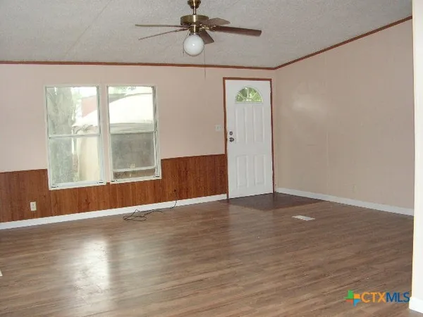 an empty room with wooden floor and windows