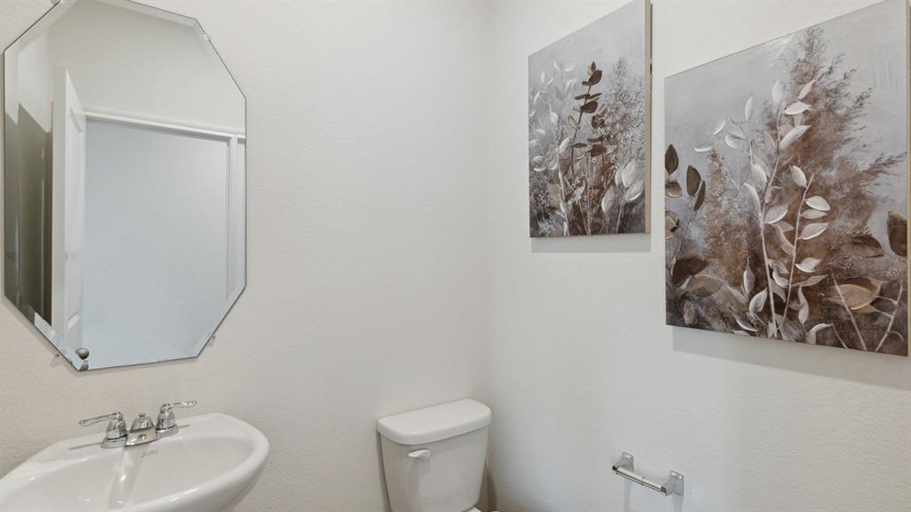 140 Pheasant Run Road Terrell, TX 75160 - Photo 13 of 26 Powder room featuring a pedestal sink with a chrome faucet, an octagonal wall mirror, and a white toilet