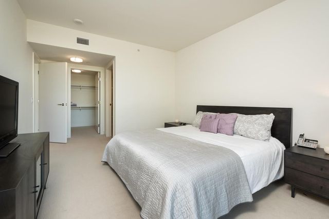 a bedroom with a bed and a flat tv screen on dresser