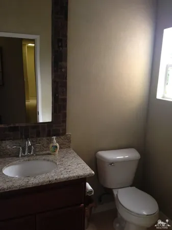 a bathroom with a granite countertop toilet sink and mirror