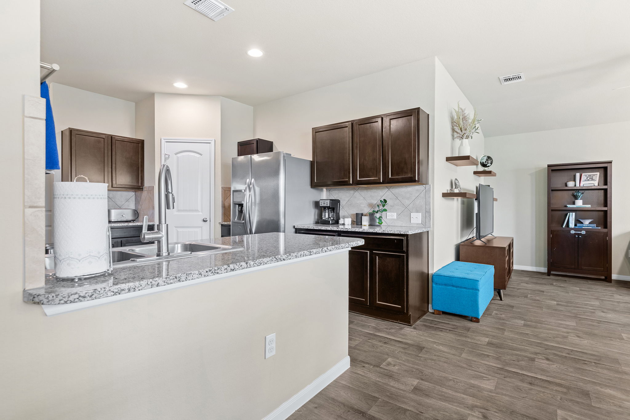 404 Cassandra Drive Hutto, TX 78634 - Photo 12 of 40 Kitchen featuring dark wood finish cabinetry, tasteful backsplash, dark wood-style flooring, a peninsula, and stainless steel refrigerator with ice dispenser