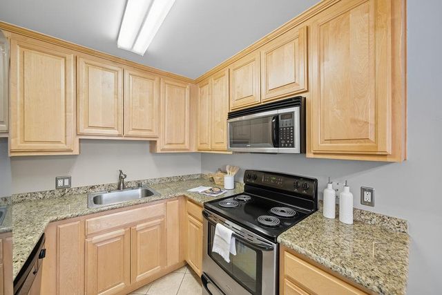 a kitchen with granite countertop a stove sink and cabinets