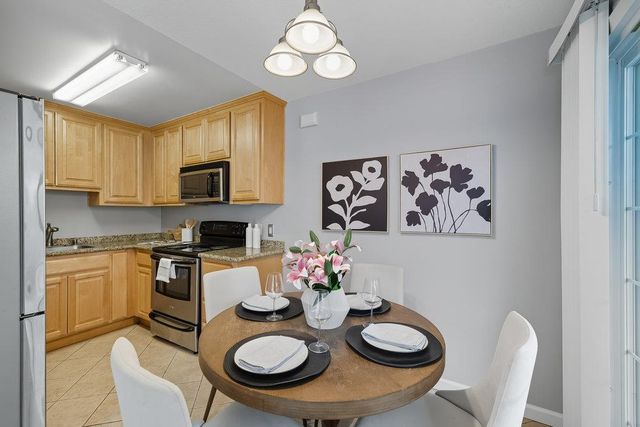 a kitchen with stainless steel appliances granite countertop a kitchen island a stove a table and chairs in it