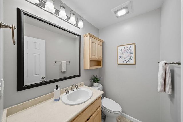 a bathroom with a sink vanity granite toilet and a mirror