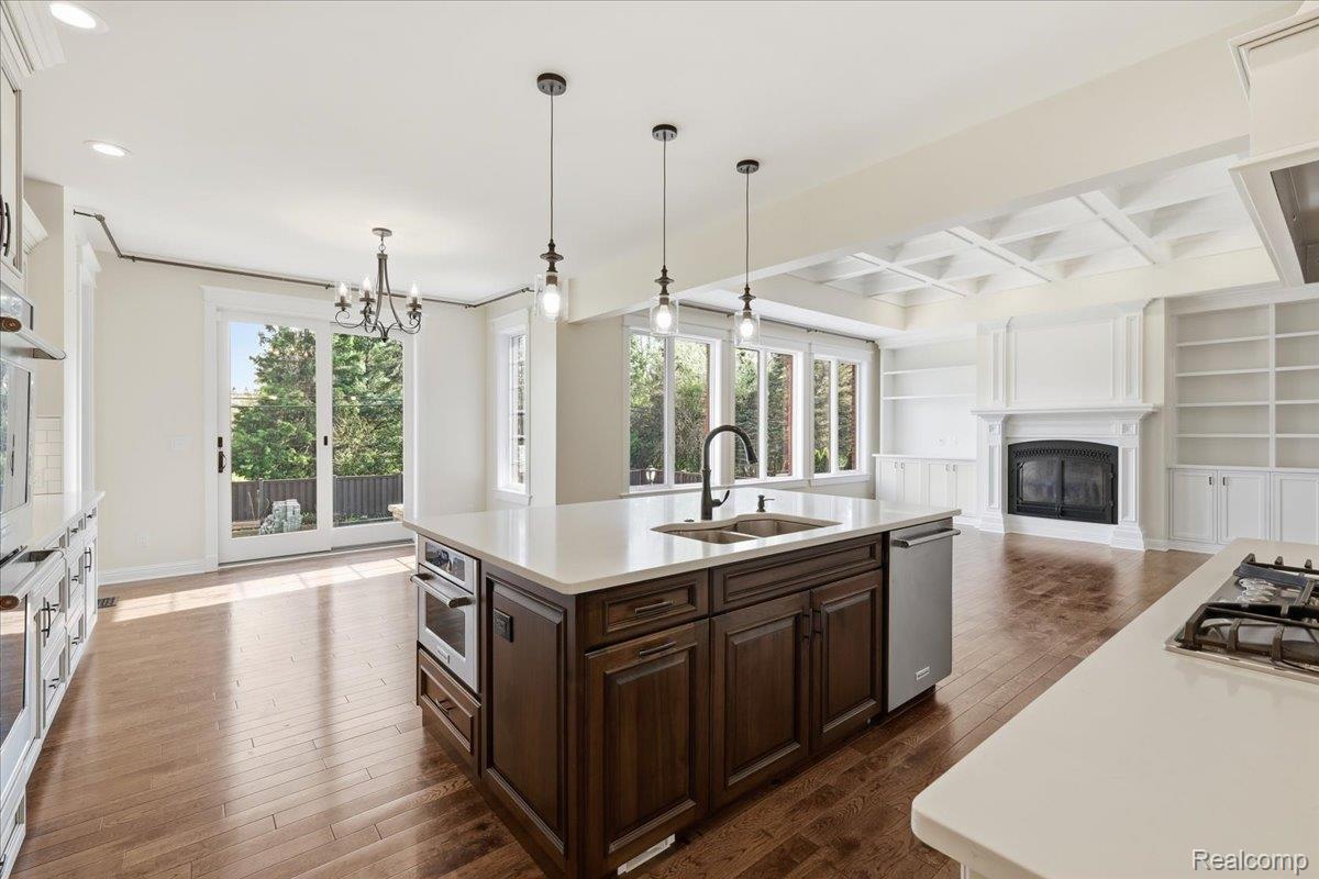 35339 West 13 Mile Road Farmington, MI 48331 - Photo 12 of 72 Kitchen with built in shelves, a kitchen island with sink, a glass covered fireplace, and coffered ceiling